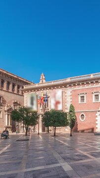 Panorama showing Patriarch's College Square in Valencia timelapse, featuring the historic Museo del Patriarca, fountain with sculptures and Church of the Patriarch. Clear blue sky, Spain.