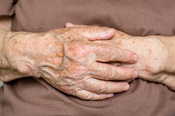 Close up cropped image hopeful grateful mature senior woman keeping hands on chest, mindful middle...