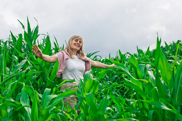 In a vibrant cornfield under golden sunlight, a joyful young woman dances with her arms raised,...