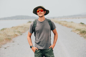 Young male tourist strolling along a coastal road, enjoying the sunny weather and vibrant ocean views