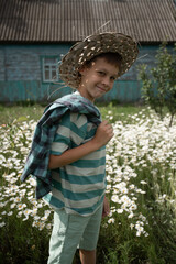 A boy in a blue striped T-shirt is standing sideways to the camera, smiling