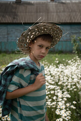 a close-up portrait of a 9-10-year-old boy wearing a hat. The child is in a village