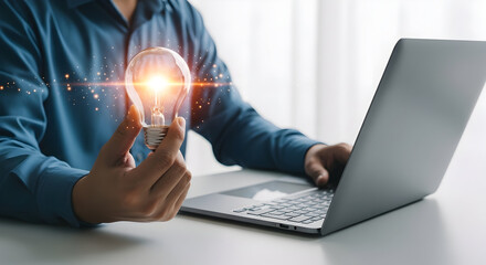 Business inspiration and solution image.Man holding lightbulb. Using smartphone and laptop.