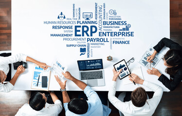 A high-angle view of a team engaged in a business strategy meeting focused on ERP, with charts and data analysis presented in a modern office setup highlighting teamwork. Amity