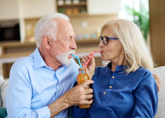 Portrait of a lovely senior  couple having fun and laughing sharing a drink together at home