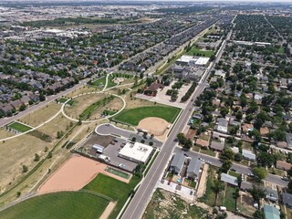 High-angle drone shot: bustling suburban landscape, multiple baseball diamonds, open parks, and homes. Excellent for sports, family, and active living