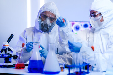 A team of chemists in hazmat suits discusses a breakthrough during a critical experiment in a...