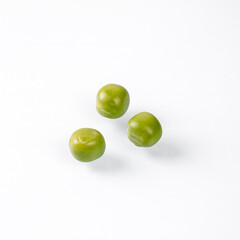 Close-up of three fresh green peas on a clean white background
