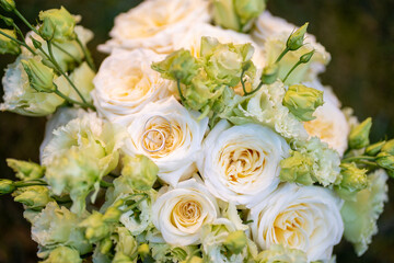 Elegant wedding bouquet of soft ivory and pastel peach roses with delicate green buds. Two gold...