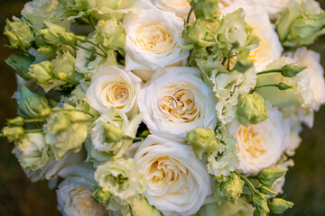 Elegant wedding bouquet of soft ivory and pastel peach roses with delicate green buds. Two gold wedding rings rest on the center rose, symbolizing love and commitment. Perfect for wedding invitations