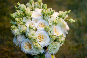 Elegant wedding bouquet of soft ivory and pastel peach roses with delicate green buds. Two gold...