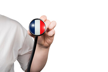 The head of a medical stethoscope in the shape of the French flag in a hand (close-up) on a...