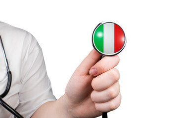 The head of a medical stethoscope in the form of the Italian flag in a hand (close-up) on a...