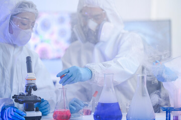 A team of chemists in hazmat suits discusses a breakthrough during a critical experiment in a...