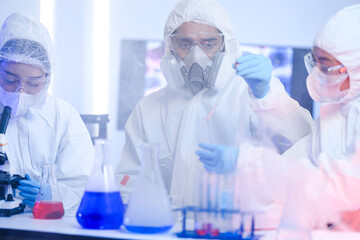 A team of scientists in hazmat suits works on a vaccine in a high-security biocontainment lab....