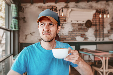 Customer showing dissatisfaction with his coffee while sitting in a cafe, expressing disappointment...