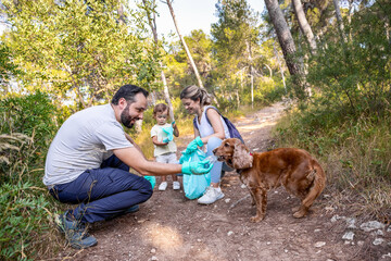 Dog joins family during trash cleanup in the forest