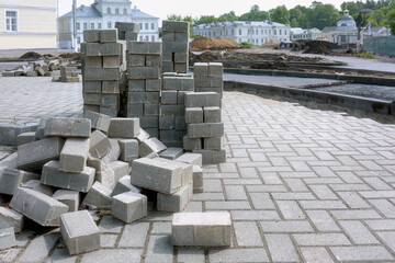 Stacked old paving slabs lying on a block pavement. Gray rectangular slabs on a paved road.