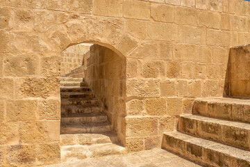 Close-up of a historic fortress wall with warm texture, an archway, and an old staircase on a...