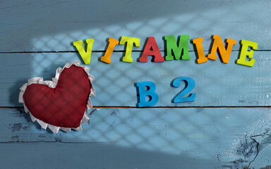 Vibrant Display of Vitamin B2 With Heart Symbol on Blue Wooden Background