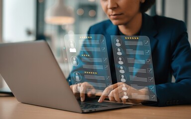 Businesswoman using a laptop with a virtual interface for human resources management, reviewing candidate profiles for recruitment.