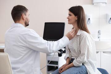 Sonographer conducting ultrasound examination of woman's thyroid gland in clinic