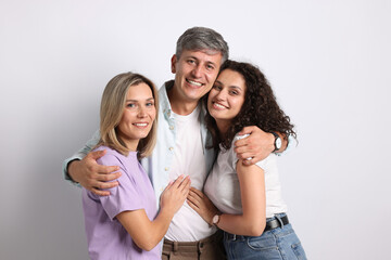 Portrait of happy friends hugging on grey background