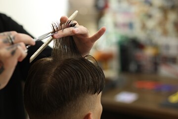 Professional barber cutting client's hair with scissors in barbershop, closeup. Space for text