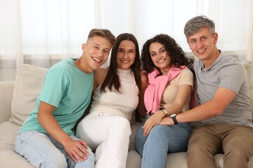 Happy friends hugging and having fun on sofa at home