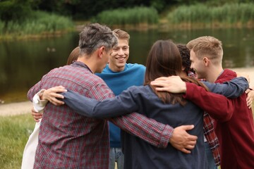 Team building. Group of happy people hugging outdoors