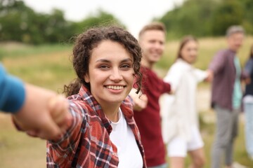 Team building. Group of happy people holding hands outdoors, selective focus