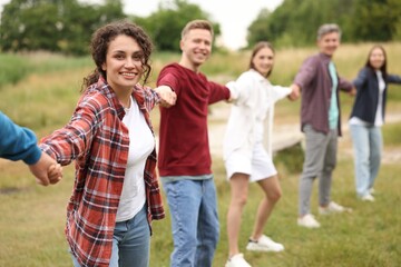 Team building. Group of happy people holding hands outdoors, selective focus