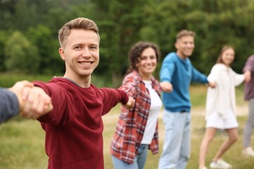 Team building. Group of happy people holding hands outdoors, selective focus