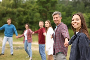 Team building. Group of happy people holding hands outdoors, selective focus