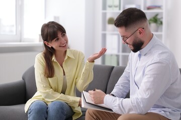 Professional psychologist working with patient on sofa in office