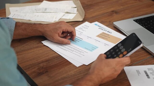 Mature man examines bills totaling up combined costs of utilities, male accountant compiles comprehensive report analyzing household expenses of company slow motion