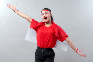 Joyful Indonesian girl expresses pride and excitement for Independence Day. Wearing red and white...
