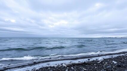 Cloudy seashore with calm waves and rocky beach