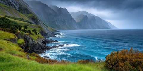 Ocean waves crashing on rocky coast with green grass and dramatic cliffs in background