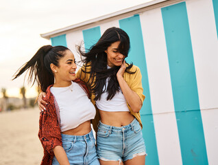 Portrait of two beautiful cheerful young women resting  on the beach. Laughing girlfriends in the...