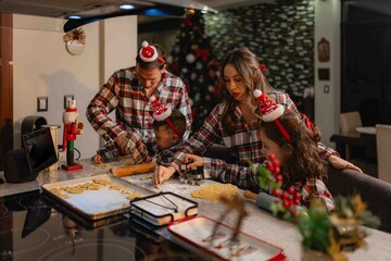 Hispanic parents and children baking Christmas cookies at home kitchen