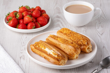 Delicious eclairs served with fresh strawberries and coffee in a cozy breakfast setting