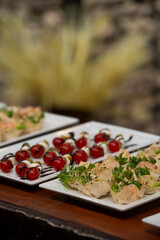 Gourmet shrimp wraps with fresh lettuce and sprouts served on a white platter. In the background,...
