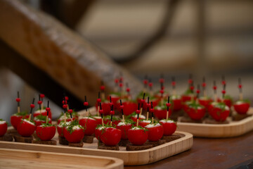 Delicious appetizer bites with cherry tomatoes stuffed with creamy filling, topped with herbs, served on rye bread squares and skewered with decorative sticks. Catering, events, and food blog concept