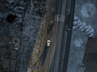 Top-down aerial view of a snowy Tallinn road in the Seaplane Harbour district. A lone electric car...