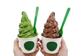 Two hands holding cups of green tea and chocolate soft serve with green spoons on a plain setting on transparent background