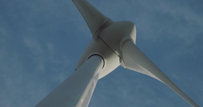 Wind turbine windmill turning in a blue sky with clouds