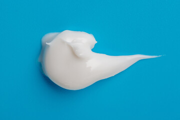 Cosmetic white cream smear on blue background. Beauty skincare creamy product. White lotion texture