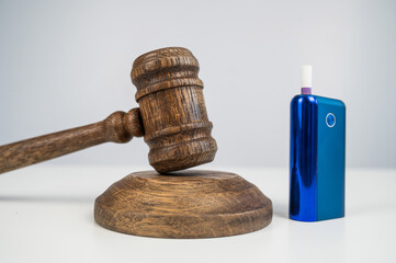 Judge's gavel and e-cigarette. Smoking ban. Tobacco heating systems. 