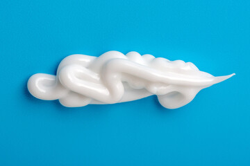 Cosmetic white cream smear on blue background. Beauty skincare creamy product. White lotion texture